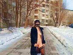 Nude tomboy in a fur coat swings on a swing in winter